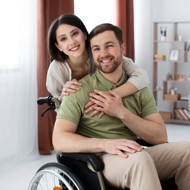 Pareja sonriente en casa, él en silla de ruedas