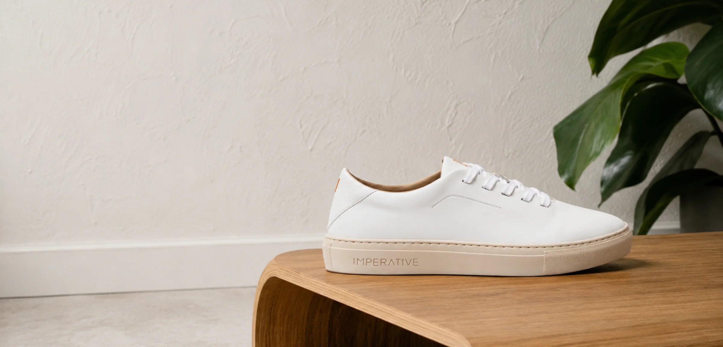 Zapatilla Bauhaus blanca de Imperative, vegana y hecha en España, sobre un banco de madera