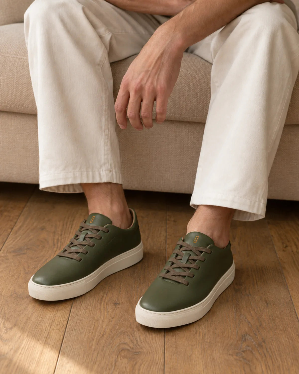 Bauhaus ever green con pantalón crudo, sentado en un sofá